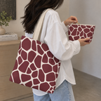 Burgundy cream giraffe print tote bag on the shoulder with the matching makeup bag