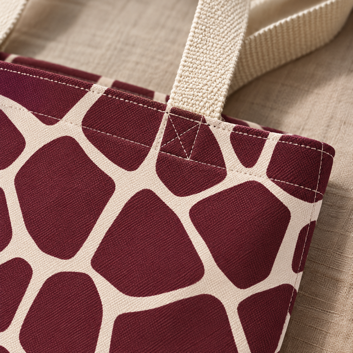 Close-up of burgundy giraffe patches with cream lines and the tote bag handle