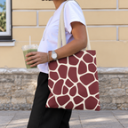 Woman walking with a burgundy cream giraffe print tote bag over her shoulder