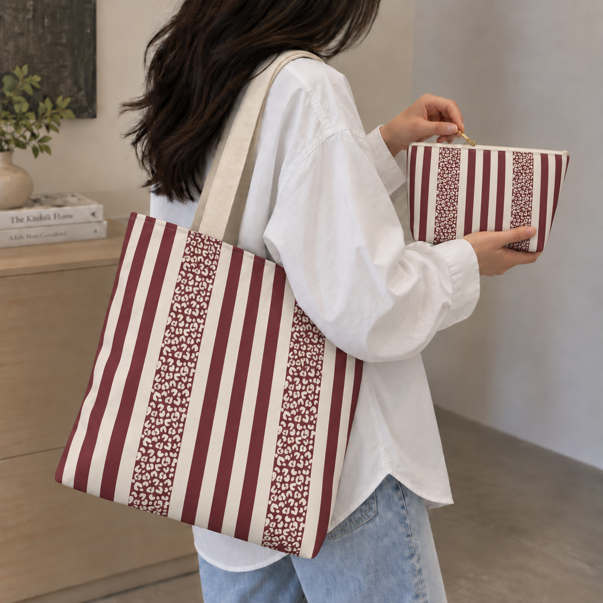 Woman carrying a burgundy striped tote bag and matching makeup bag