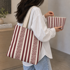 Burgundy cream striped tote bag on the shoulder with the matching makeup bag