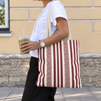 Side view of a woman carrying a burgundy cream leopard striped tote bag