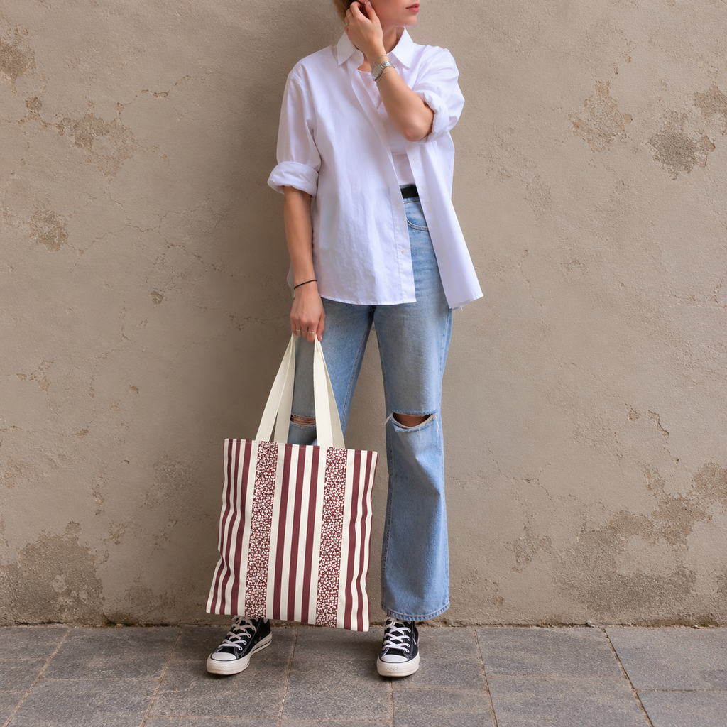 Woman leaning on a wall with a burgundy cream leopard striped tote bag