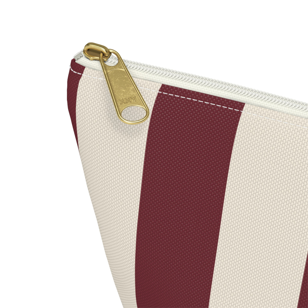 Close-up of the gold zipper pull and burgundy stripe on the makeup bag