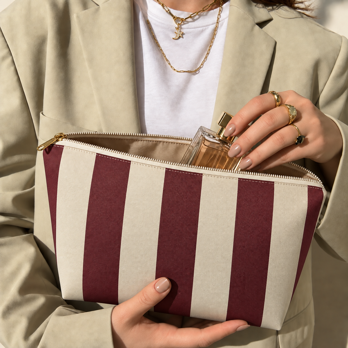 Hands holding the open burgundy cream striped makeup bag