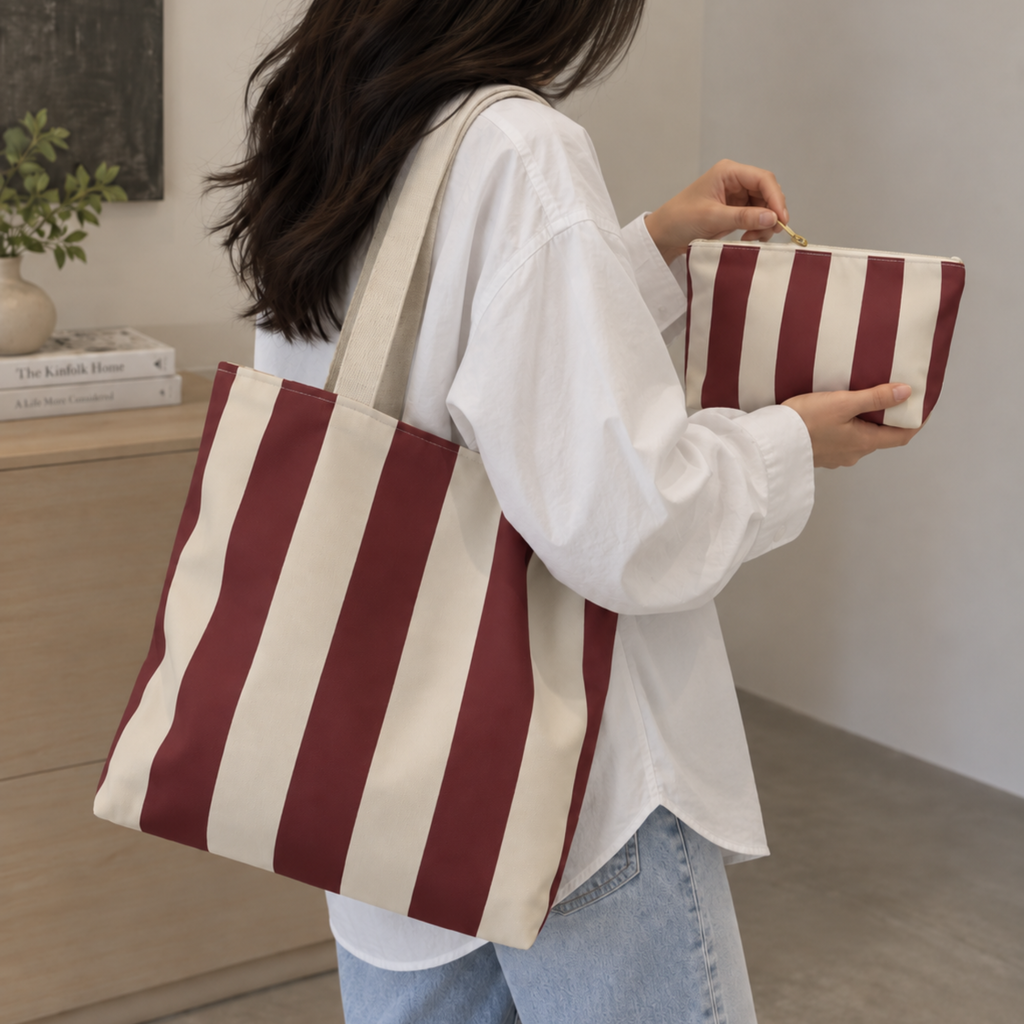 Woman wearing the burgundy cream striped tote bag with the matching makeup bag in her hand