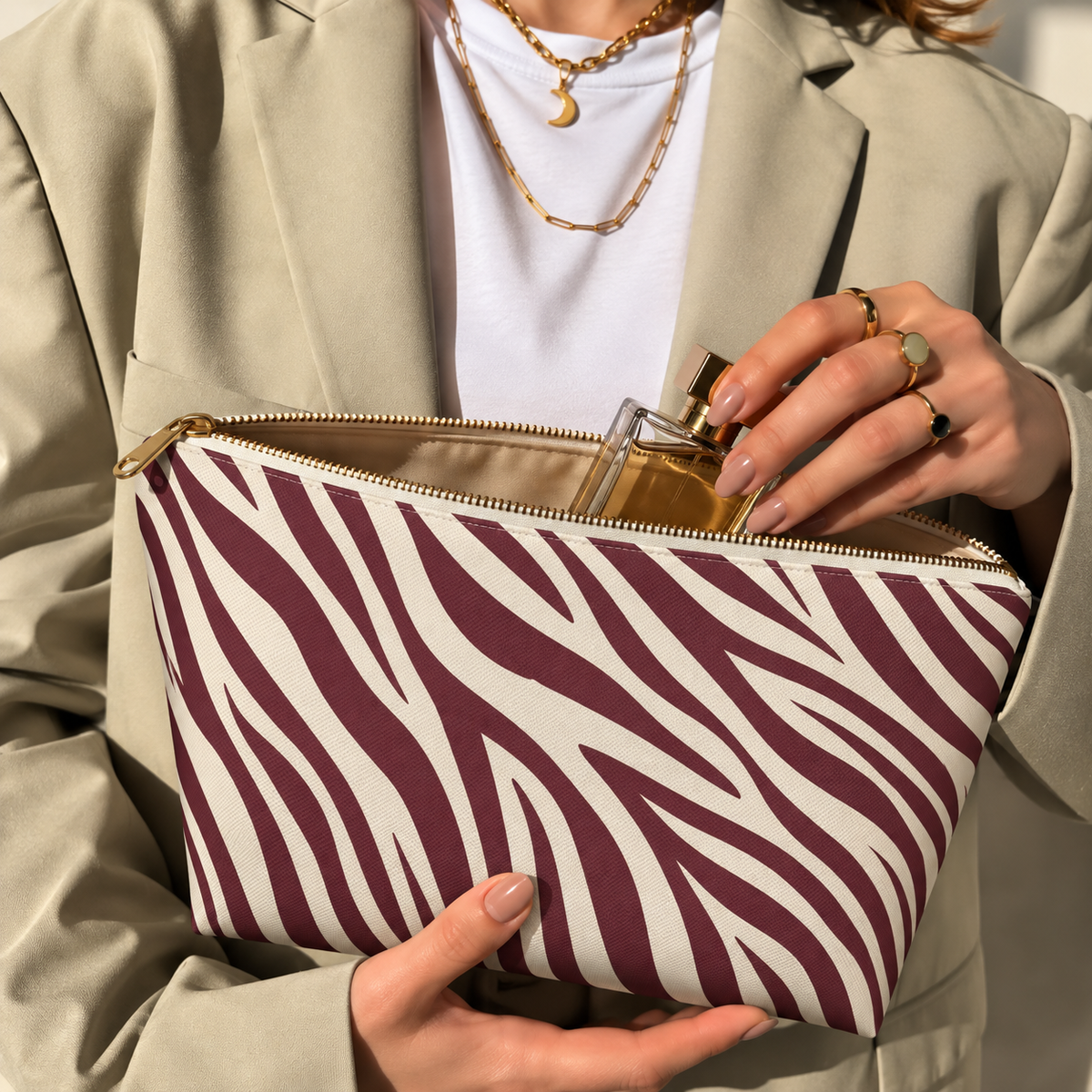 Woman opening the burgundy zebra print makeup bag to take out a perfume bottle