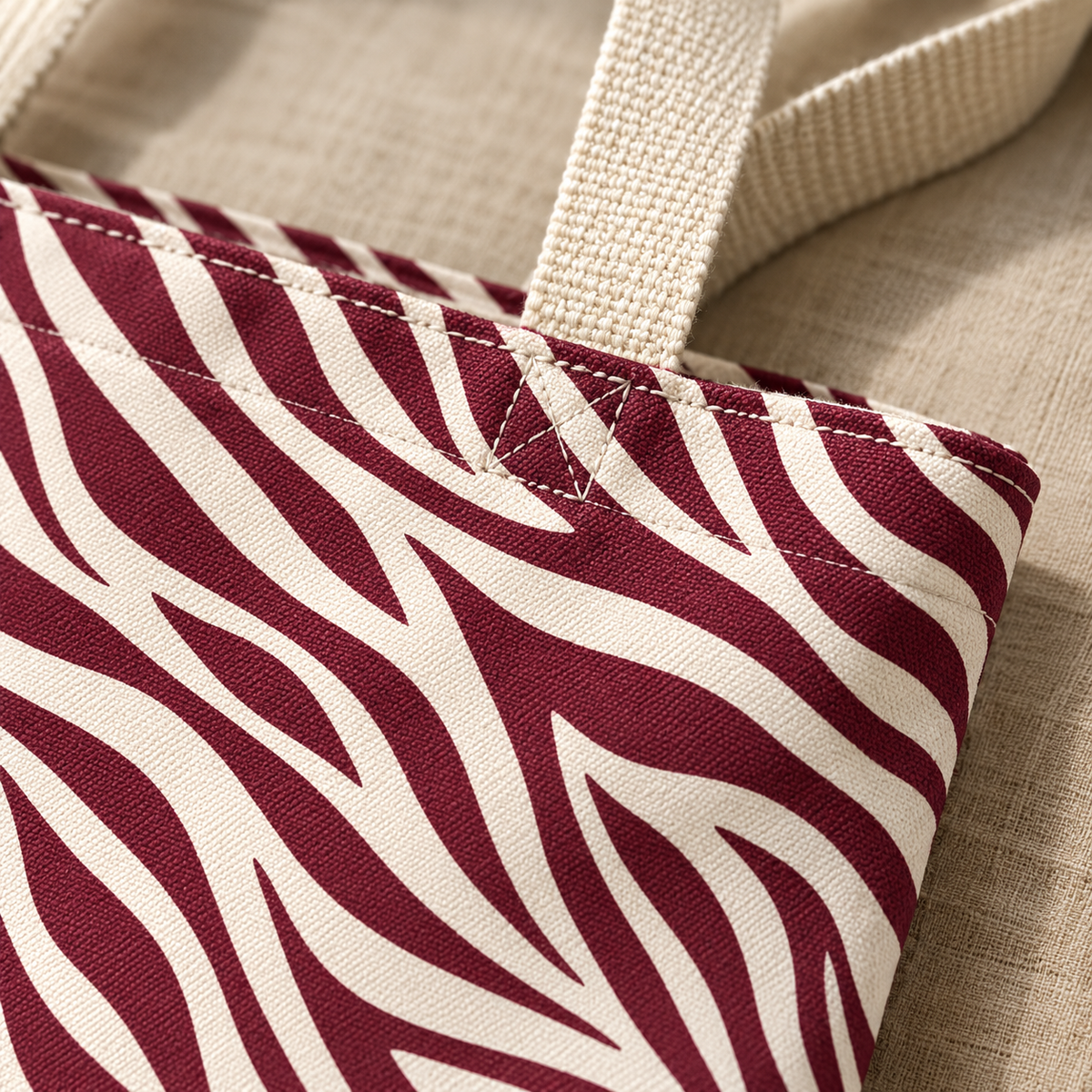 Close-up of the burgundy zebra stripes and cream handle of the tote bag