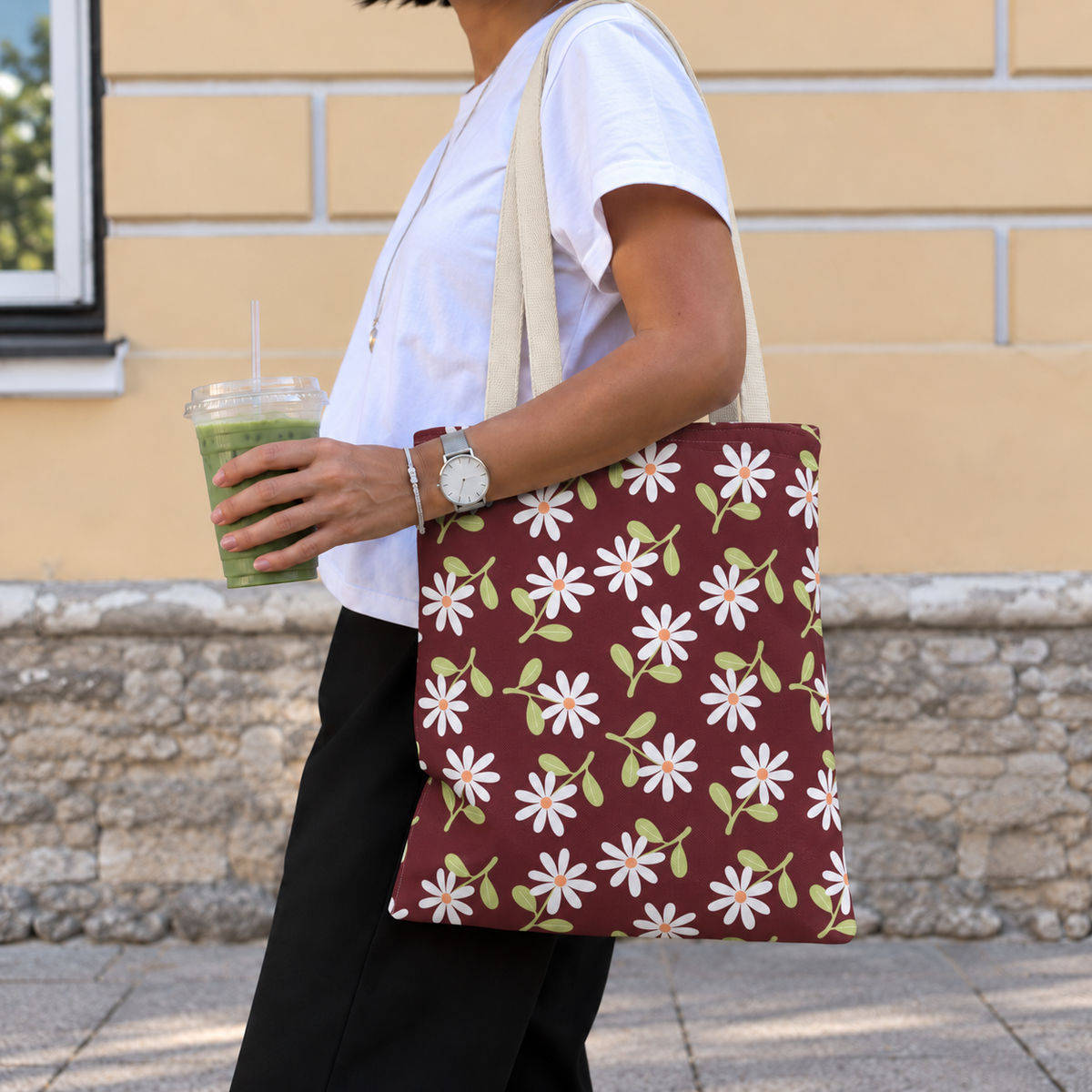 Side view of a model carrying the daisy floral tote bag in burgundy