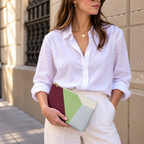 Model in a white shirt holding the burgundy green color block makeup bag at her waist