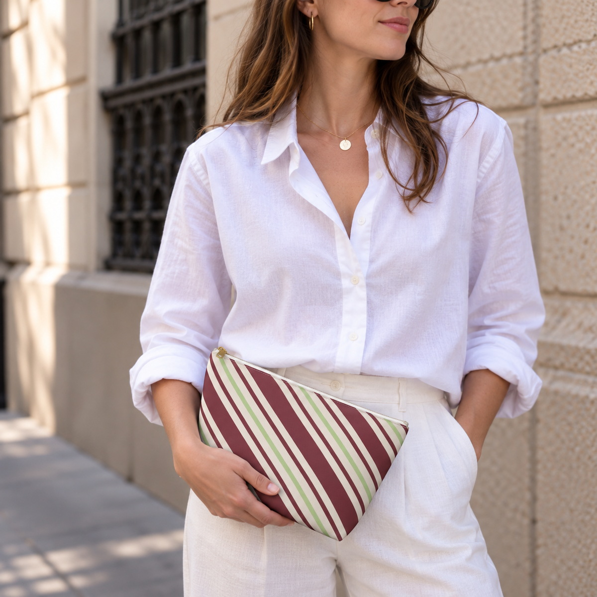 Woman in a white shirt holding the diagonal striped makeup bag as a clutch