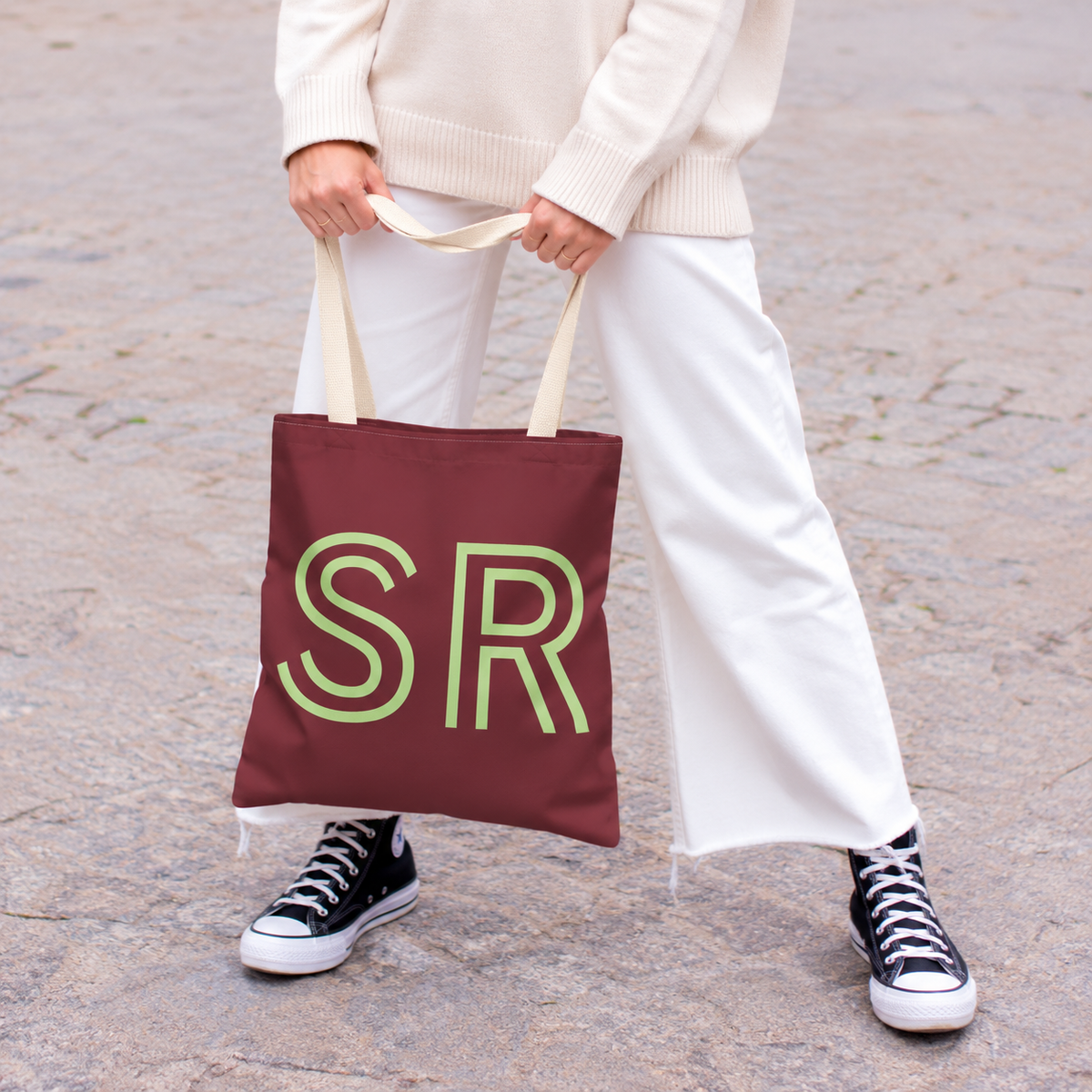Model holding the Burgundy Green Monogram personalized tote bag in front of white trousers