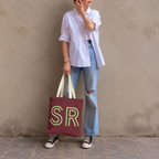 Model standing outdoors with the Burgundy Green Monogram personalized tote bag in a full-body photo