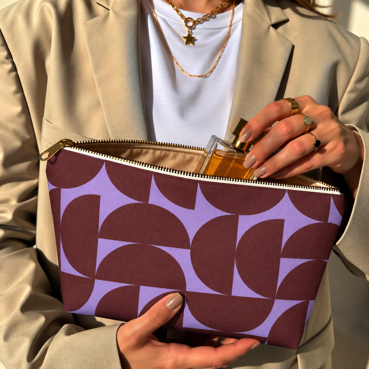 Model in a beige blazer taking a product out of the open burgundy lilac half circle makeup bag