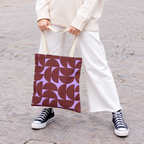 Model holding the burgundy lilac half circle tote bag in front of white trousers