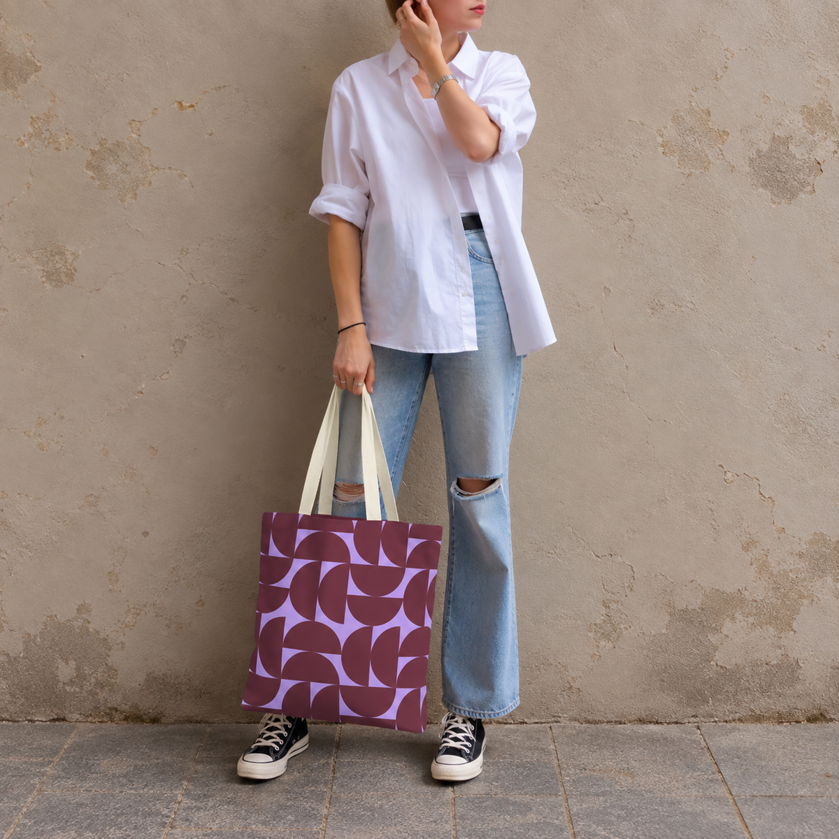 Model in jeans and a white shirt standing with the burgundy lilac half circle tote bag