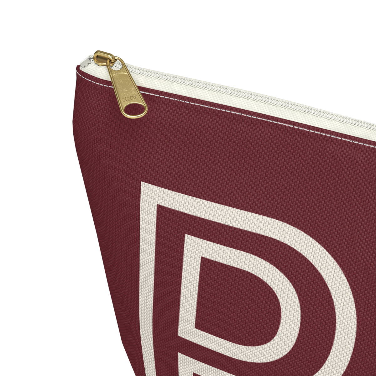 Close-up of the gold zipper pull and cream letter on the burgundy personalized makeup bag