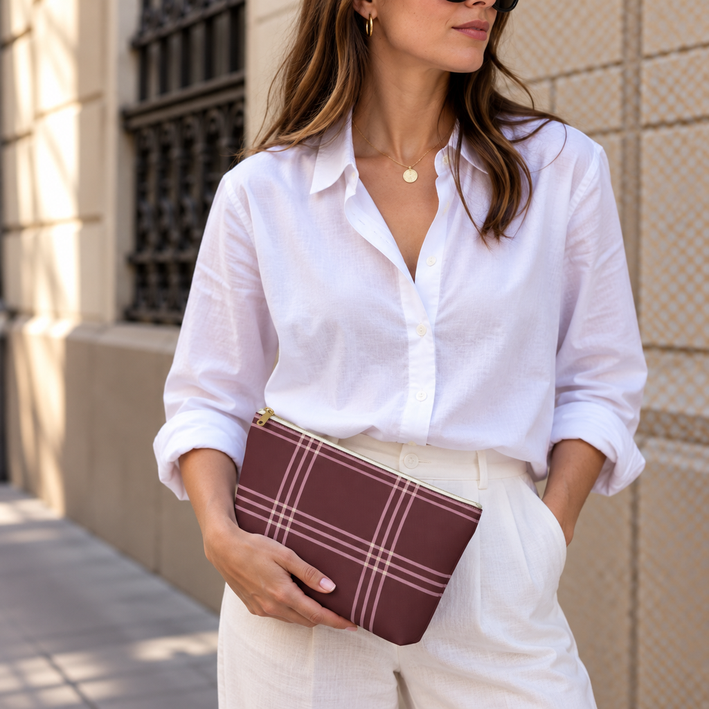 Model in a white shirt holding the burgundy pink plaid makeup bag as a clutch