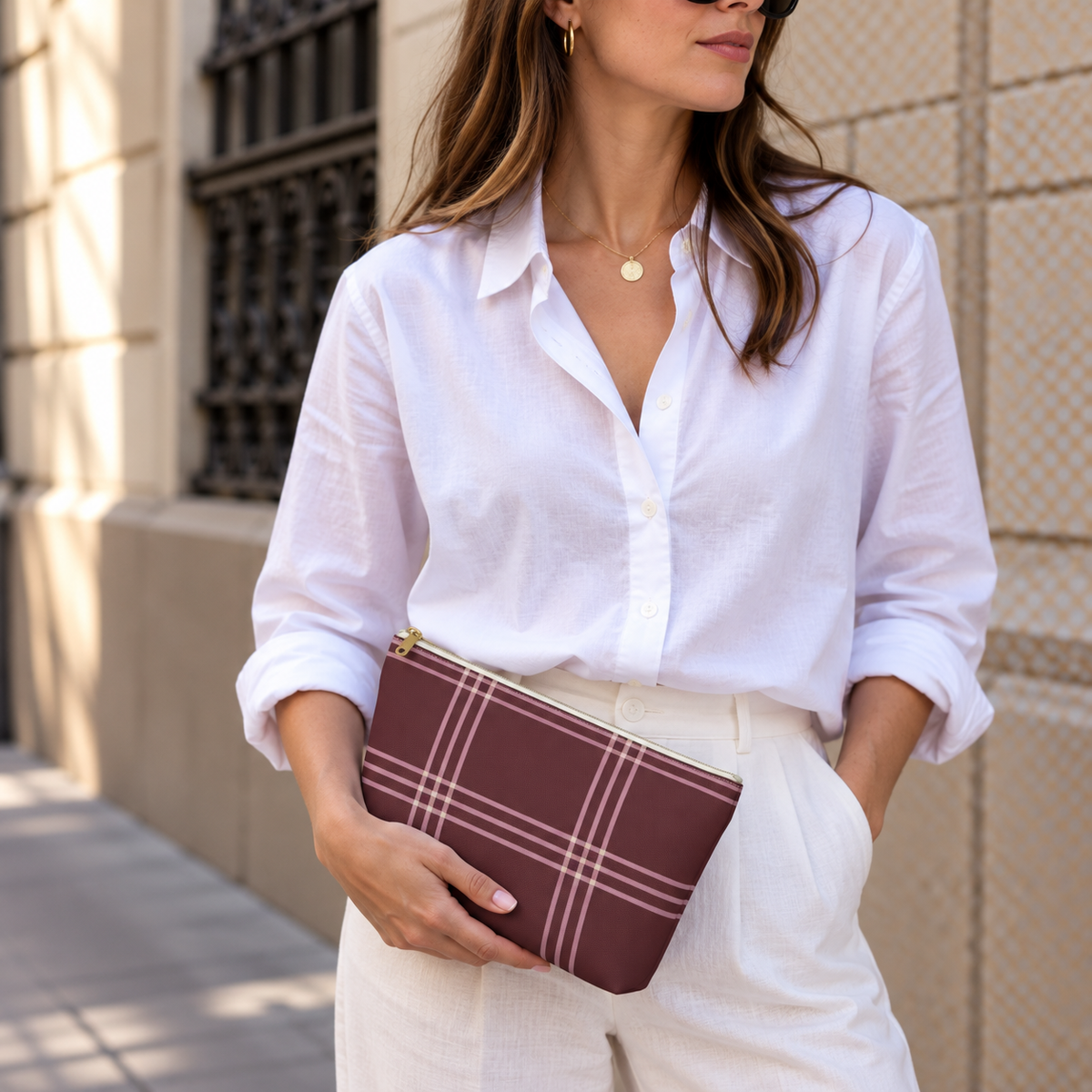 Model in a white shirt holding the burgundy pink plaid makeup bag as a clutch