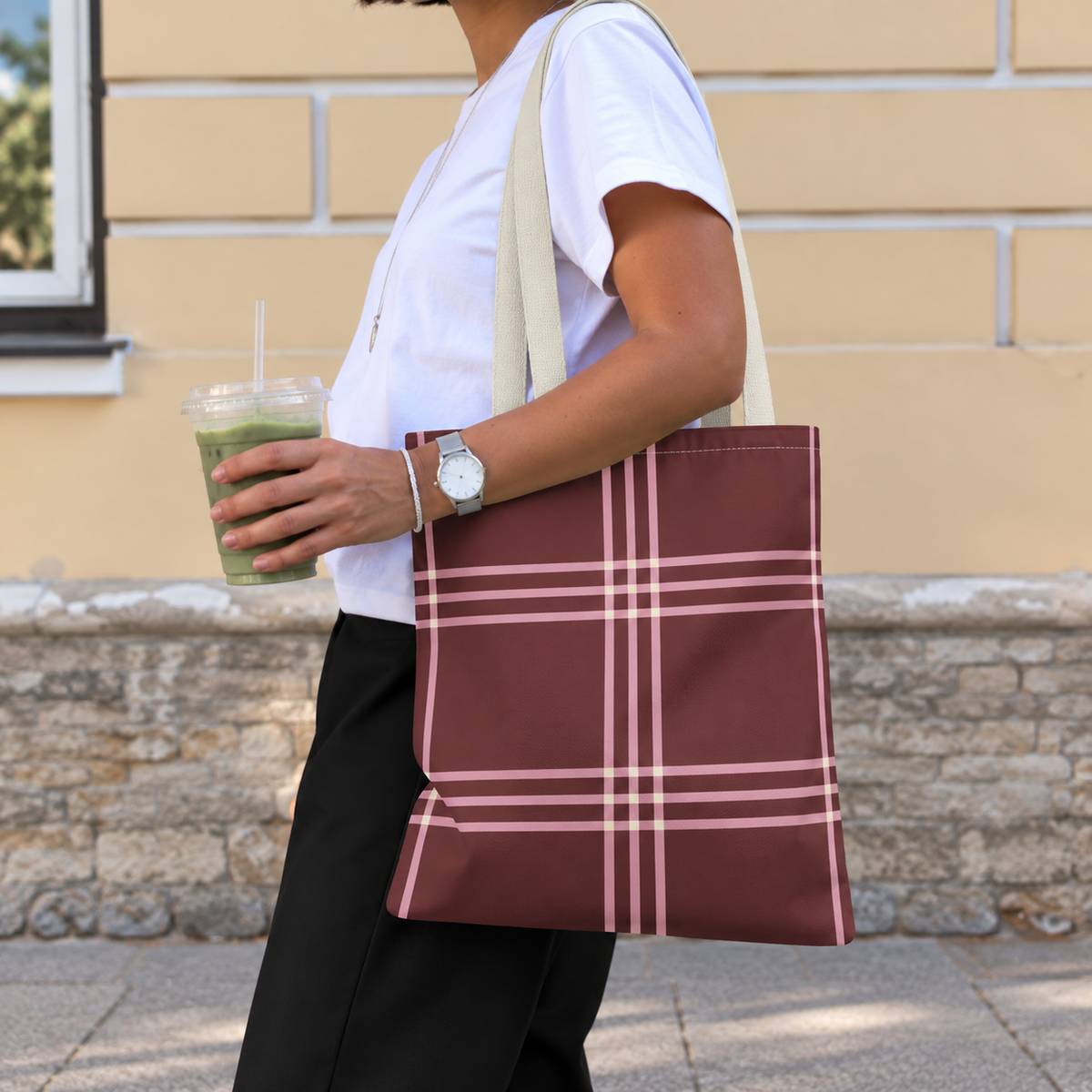 Side view of a model carrying the burgundy pink plaid tote bag on the shoulder