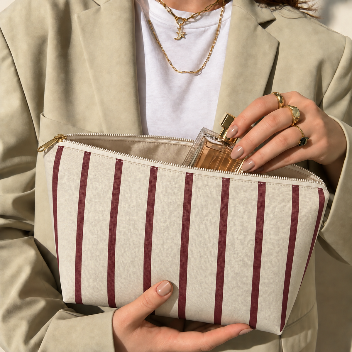 Hands holding the open burgundy pinstripe makeup bag