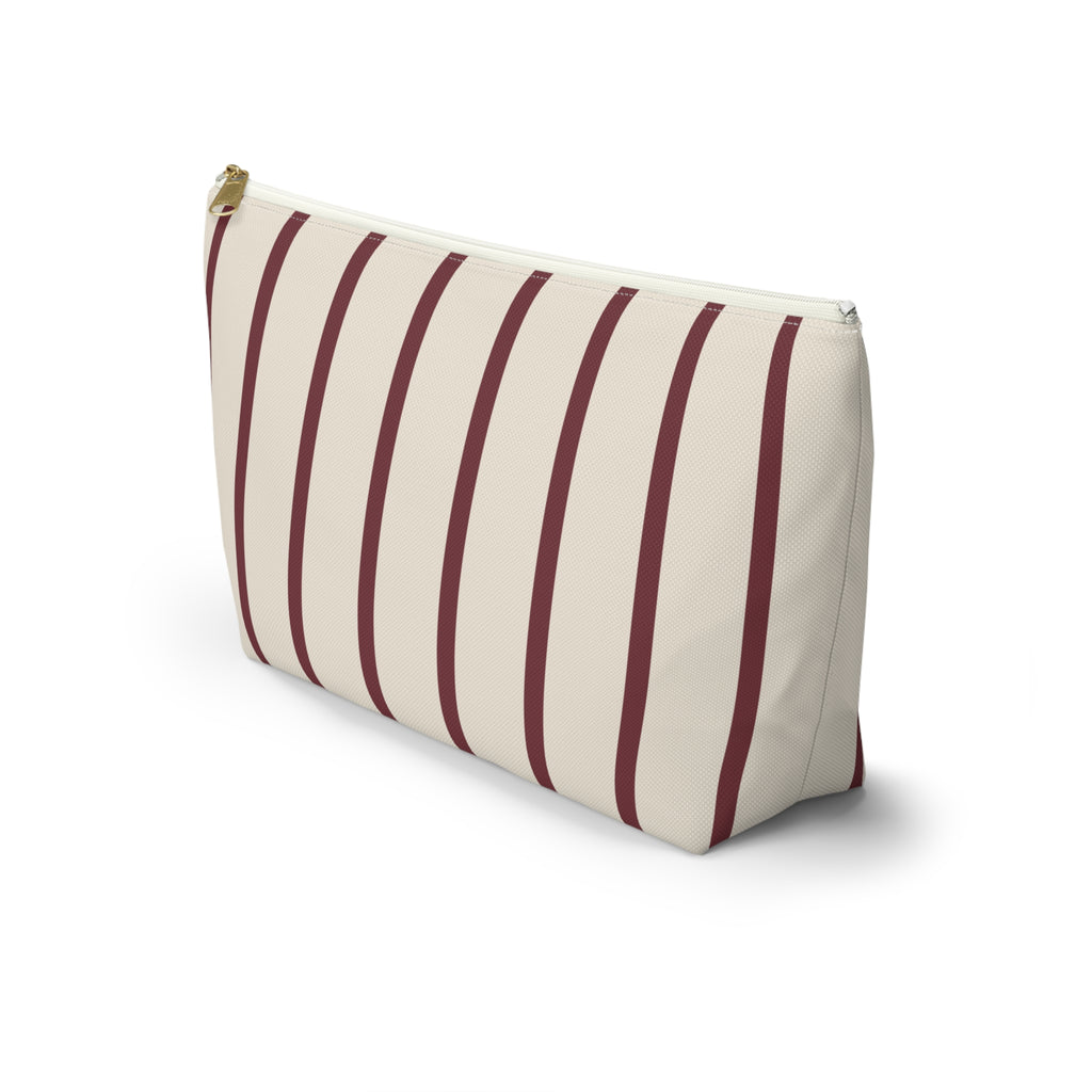 Side view of the burgundy pinstripe makeup bag standing on a white background