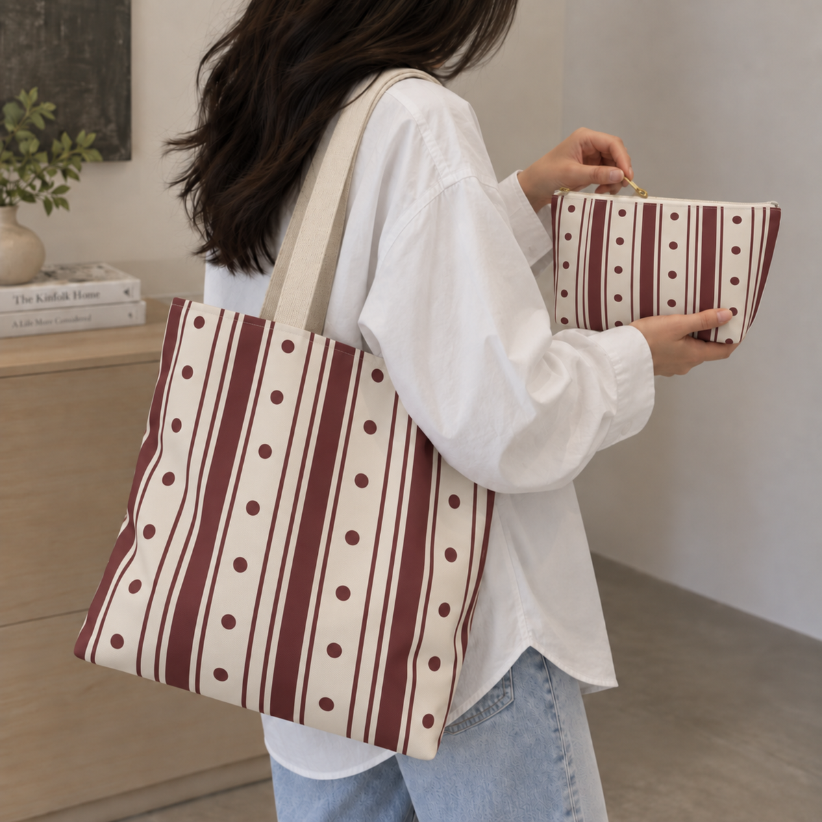 Woman wearing the burgundy polka dot striped tote bag with the matching makeup bag in her hand