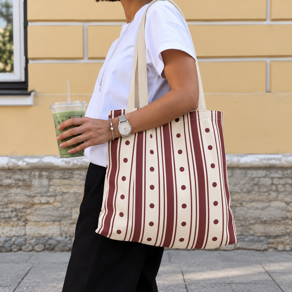 Woman carrying the burgundy polka dot striped tote bag on her shoulder on the street