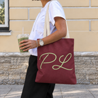 Side view of a model carrying the burgundy monogram tote bag with sage green script initials