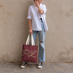 Model in jeans standing with the burgundy monogram personalized tote bag