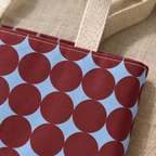 Close-up of the burgundy circles on sky blue and the handle of the geometric tote bag
