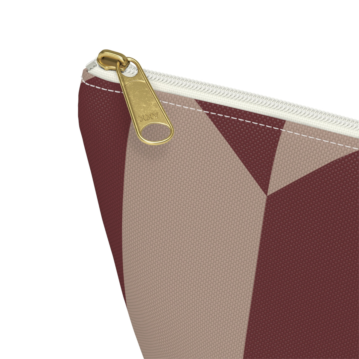 Close-up of the gold zipper pull on the burgundy taupe geometric makeup bag