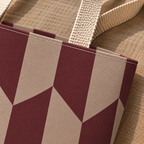 Close-up of the burgundy and taupe angled panels and beige handle on the tote bag