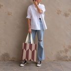 Model in jeans and a white shirt standing with the burgundy taupe geometric tote bag