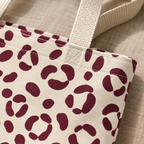 Close-up of burgundy leopard spots on cream fabric and the tote bag handle