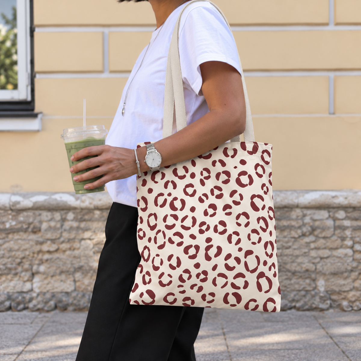 Woman walking with a cream and burgundy leopard print tote bag over her shoulder