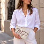 Model in a white shirt holding the cream monogram makeup bag at her waist