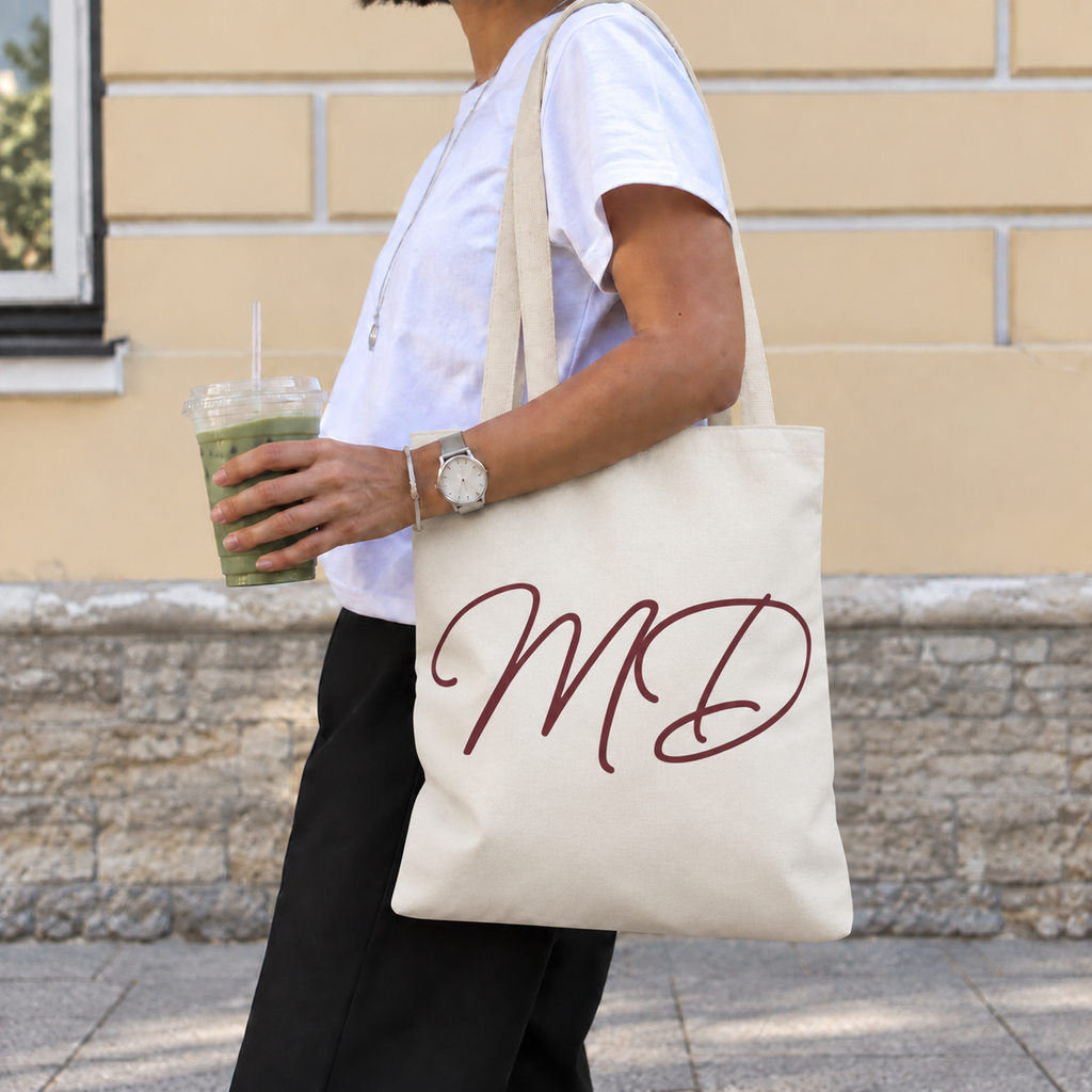 Side view of a model carrying the cream monogram tote bag with burgundy initials
