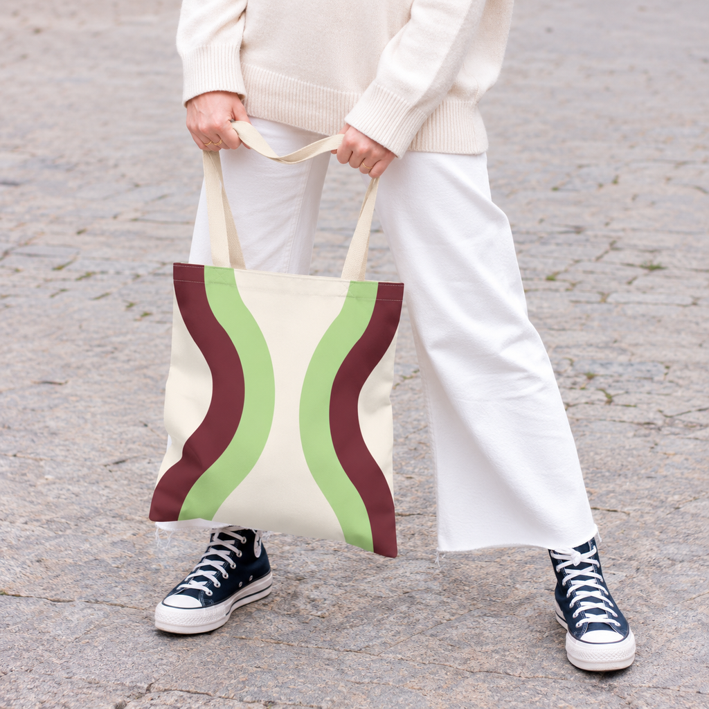 Model holding the Cream Green Burgundy Wavy tote bag in front of white trousers