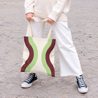 Model holding the Cream Green Burgundy Wavy tote bag in front of white trousers