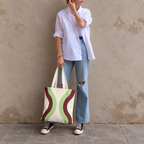 Model standing outdoors with the Cream Green Burgundy Wavy tote bag in a full-body photo
