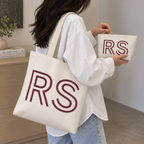 Woman carrying the cream RS monogram tote bag with the matching makeup bag