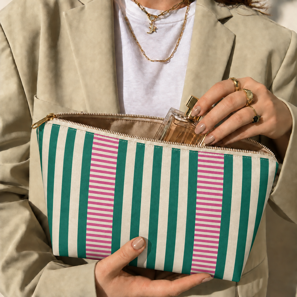 Hands holding the open Emerald Green Pink Striped makeup bag filled with cosmetics