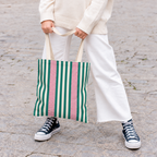 Model in white trousers carrying the Emerald Green Pink Striped tote bag