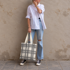Woman in white shirt and jeans standing with the gray cream plaid tote bag