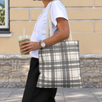 Side view of a person carrying the gray cream plaid tote bag on the shoulder