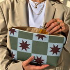 Model in a beige blazer taking a product out of the open green blue star checkered makeup bag