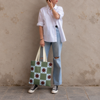 Model in jeans and a white shirt standing with the green blue star checkered tote bag