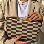 Woman holding the green burgundy checkered makeup bag open with the gold zipper