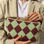 Hands holding the green burgundy checkered makeup bag with a perfume bottle inside
